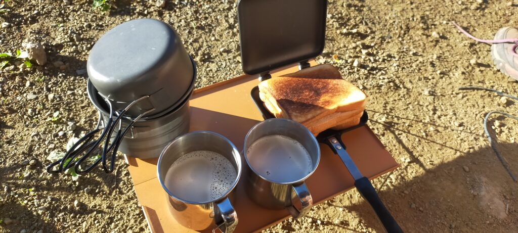 A small orange table with a sandwich and 2 coffees on the top