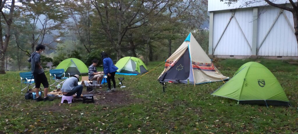 Green area with 4 tents, people are preparing the dinner