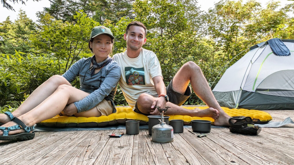 Nomin and Hiro camping and looking at the camera